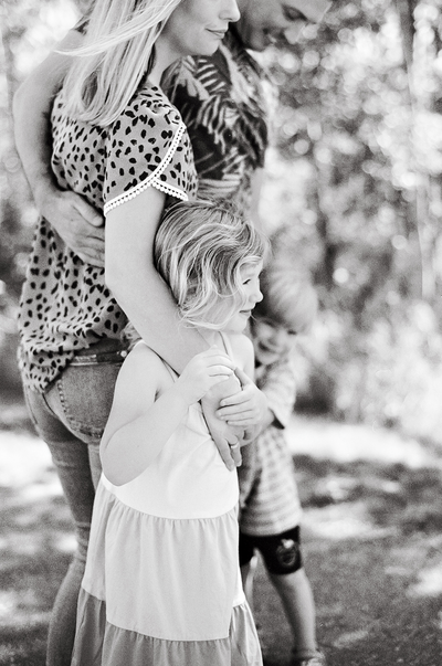 a little girl hugs her mom while standing with her family