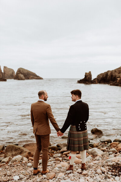 groom and groom hold hands at the sea