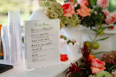 White bar menu with green watercolor calligraphy in acrylic block frame