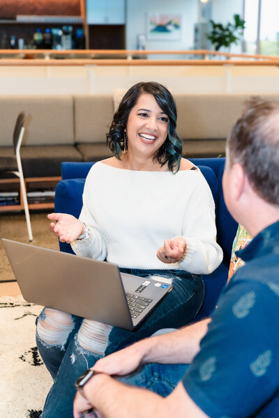 brand photo of a business Coach talking to her client, laptop in her lap and client looking at her