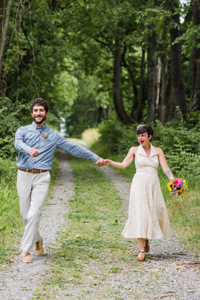 Bride and Groom in a white wedding dress and blue shirt and khaki pants holding hands at their outdoor wedding ceremony.