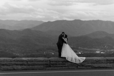 black and white elopement photos with couple in the Foothills Parkways kissing while standing on the edge of a stone wall with the mountains in the distance as they elope to Gatlinburg 