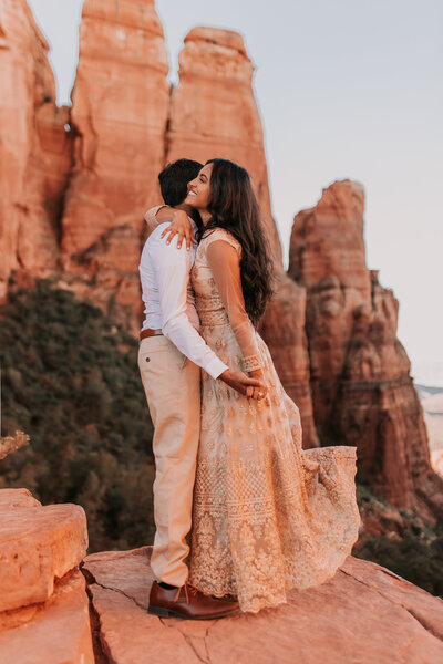 bride and groom standing on red rocks