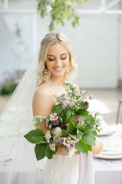 bride smiling down at wedding bouquet
