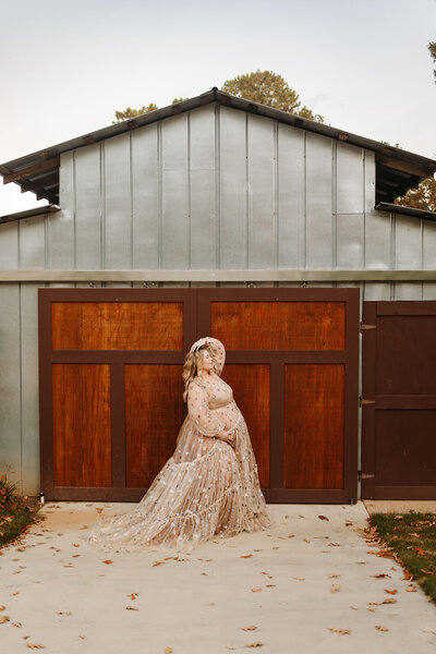 maternity photo of mom in light peach dress in front of barn