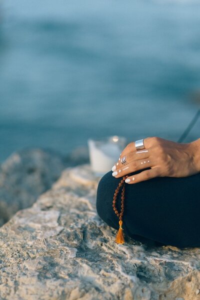Person meditating by the ocean in Puerto Escondido, Mexico, embracing the calming sound of waves and coastal breeze for deep relaxation and mindfulness.