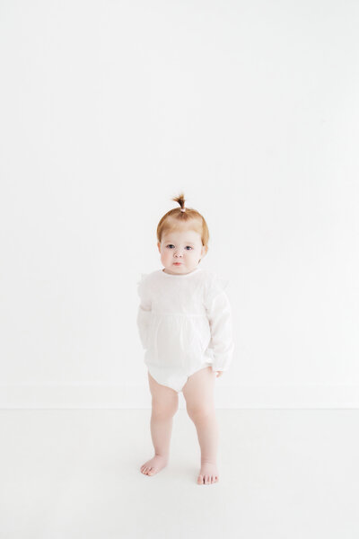 Beautiful smiling red haired baby girl on her natural baby photoshoot