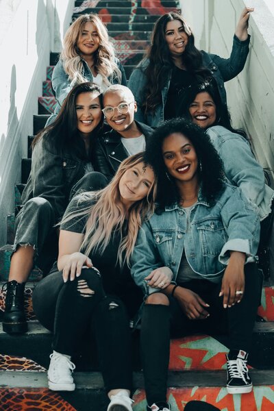 7 college senior women sitting on stairs.  Showing individuals who connected in group therapy for college students. As seniors in college these women came together in a support group with a group therapist in Manhattan, New York.