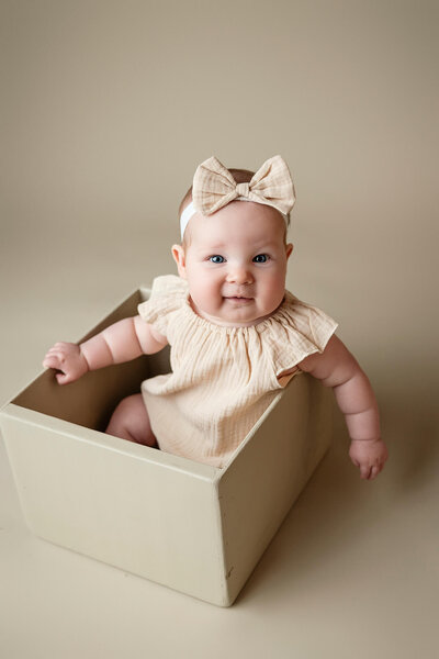 Adorable six month old baby girl posed in a crate during her Milestone Session.