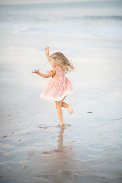 Family session of little girl dancing on the beach