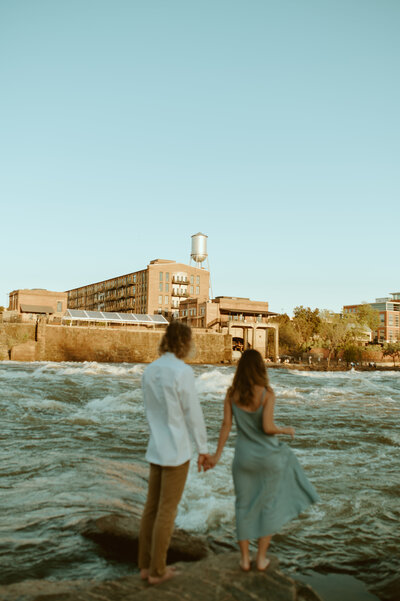 couple holding hands near a river
