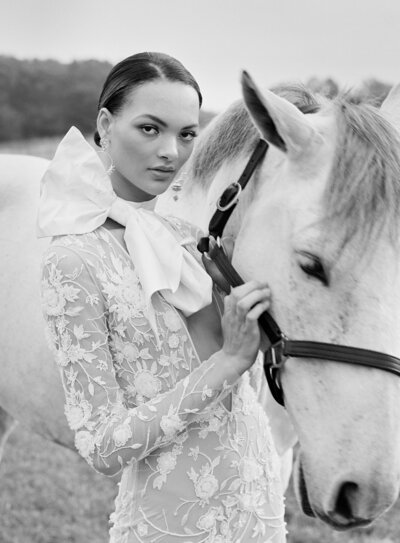 Woman standing next to a white horse.