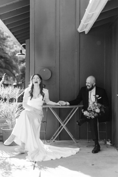 black and white photo of bride and groom laughing