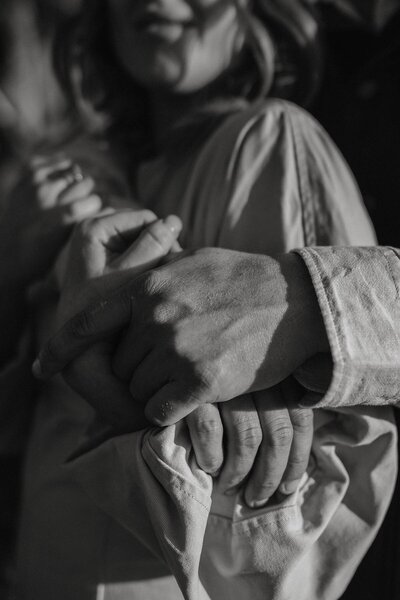 Close-up of a man holding their partner's hand during a couples photoshoot, showing connection and warmth.