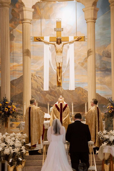 bride and groom kneeling at consecration during catholic wedding Mass
