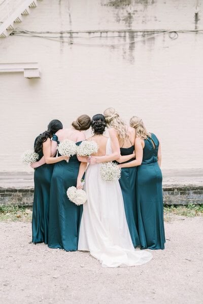 Bridesmaids embrace their bride while holding baby's breath bouquets