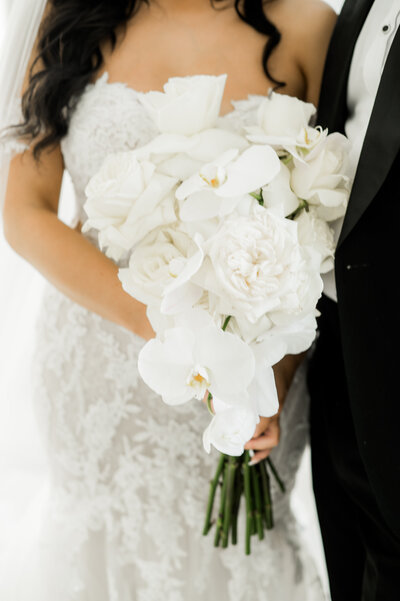 bride in white gown holding all white flower bouquet