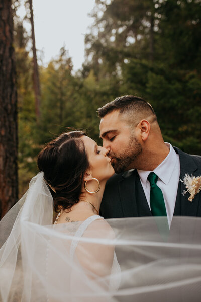 bride kisses groom as wedding veil swirls in front of them