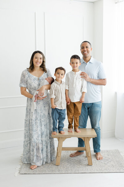 Family of 5 poses for newborn portraits in photography studio