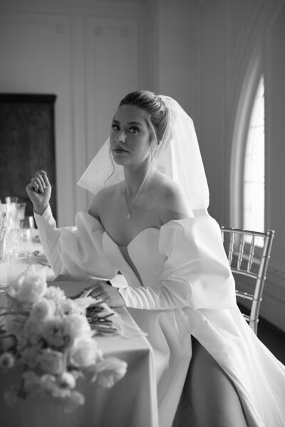Bride sitting down at table with unique veil and gown