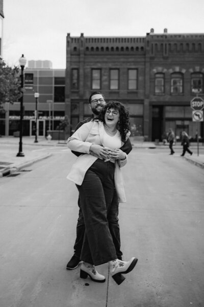 Bryan of O & B Photo Co hugs Olivia from behind as they walk down Main Street in Stevens Point, WI