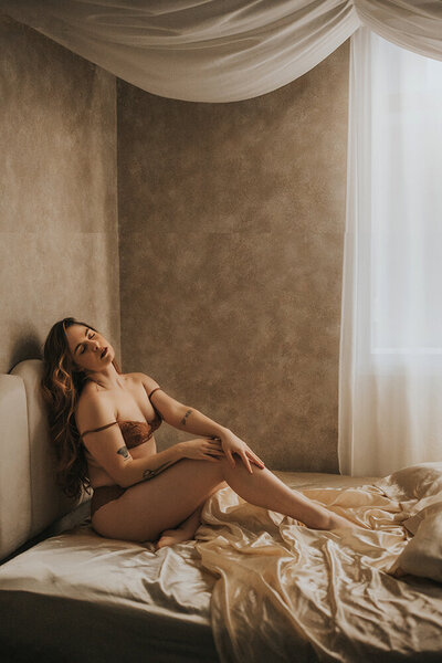 during a boudoir photoshoot, a woman is posing on a bed