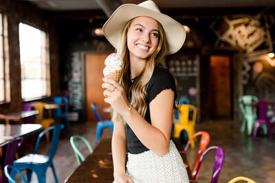 A high school senior girl eating ice cream in a colorful room at Crank and Boom ice cream in Lexington KY.