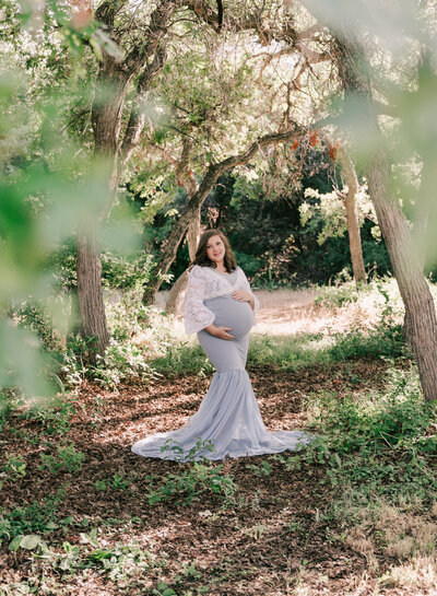 A pregnant woman stands in a gorgeous grove of trees. Photo by Diane Owen.