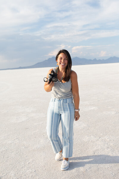 Samantha Okazaki, photographer, posing on the Salt Flats in Utah with her camera