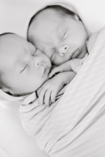 Twin baby girls swaddled together as they sleep.