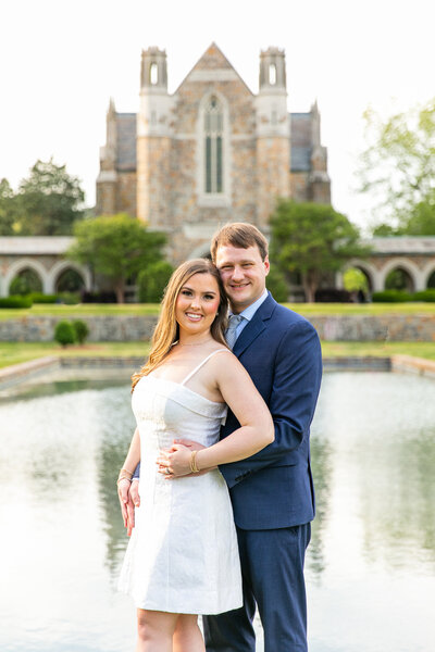 engaged couple holding hands in front of a stone building