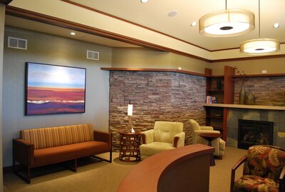 Frank Lloyd Wright-inspired waiting area in a dental office featuring original art and a fireplace, designed by EnviroMed Design. The waiting area features clean lines, geometric shapes, and natural materials, creating a calming and inviting atmosphere for patients.