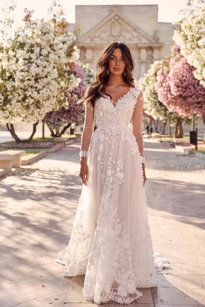 The epitome of garden weddings, Meadow is the show stopping elegance every bride wants to live out. Her lush and grandeur skirt, embellished with botanical embroidery has a very Italian couture elegance about her. Her 3D floral lace has been expertly placed to cascade from detailed clusters around her neckline, to blossoms across the thin overlay before flourishing down the full bodied gown. Meadow is a mirage of glamour designed to showcase her feminine grace with a touch of dramatic sophistication which is mirrored when she walks away. As she turns, a key-hole cut out exposes her back, as translucent lace mixed with flower appliqués climb and meld into her bodice. While she may look sweet, with her sheer long sleeves and elusive buds, she has an unexpected lust revealed in her V-neckline. Meadow is by no means a traditional ball-gown, instead she maintains a soft, full-flowing skirt that sweeps behind into a statement making train – adding just enough drama to a provincial ceremony or alfresco reception.