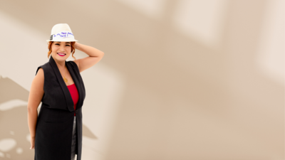 Woman standing and smiling  with a hat on a photoshoot