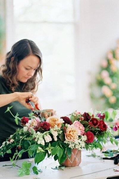 Sara Davies arranging a floral centerpiece at a wedding