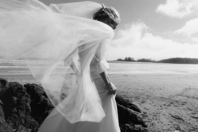 romantic photo of bride with the wind lifting up her veil in Tofino