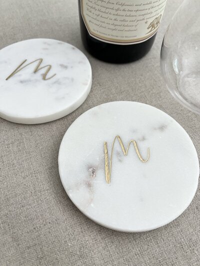 Round white marble coasters with engraved gold monogram