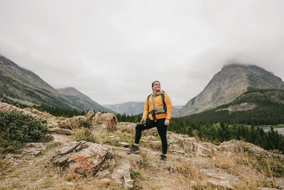Montana Elopement Photographer poses in the mountains in a yellow coat.