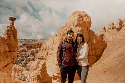 couple standing in front of red rocks