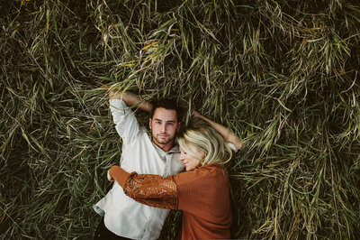 Couple laying in the tall grass with green and orange