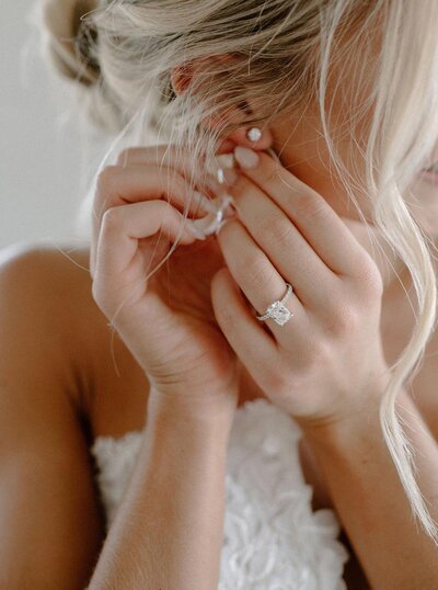 close up or bride putting on earrings