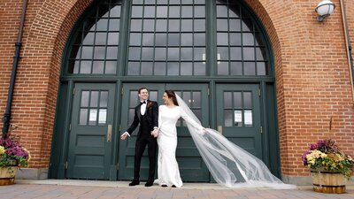 couple holding hands outside a large door