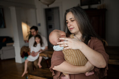Newborn resting peacefully on mother’s chest in soft window light, swaddled in a dotted muslin wrap during a calm, baby-led session in Portland.
