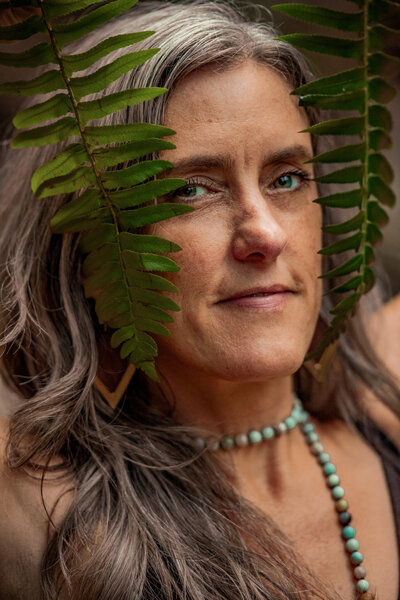 Woman wearing a necklace with leaves in front of her face