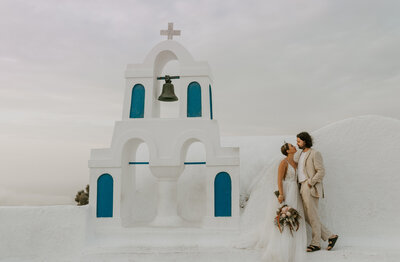 Bride and groom in front of santorini church in Oia