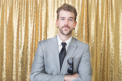 man posing elegant front of a gold backdrop