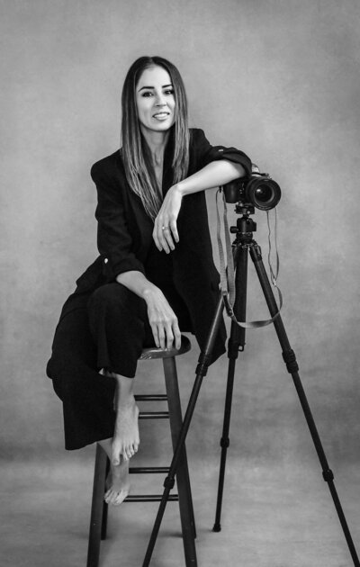 Photographer posing on a chair with camera on the side on a tripod