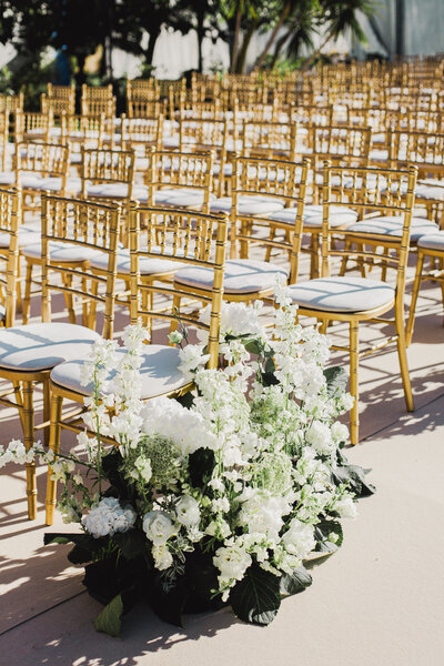 Elegant gold chiavari chairs and lush white floral arrangements set up for a ceremony at a destination wedding in Portugal.