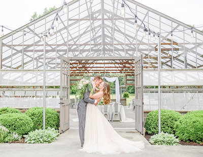 Glass atrium wedding venue photo of bride and groom kissing