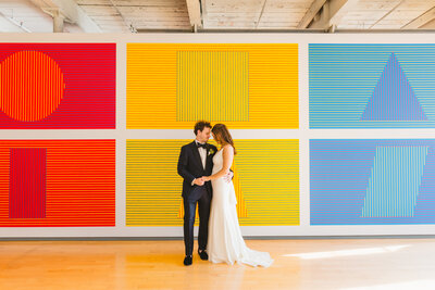Bride and Groom standing in front of colorful background on wedding day